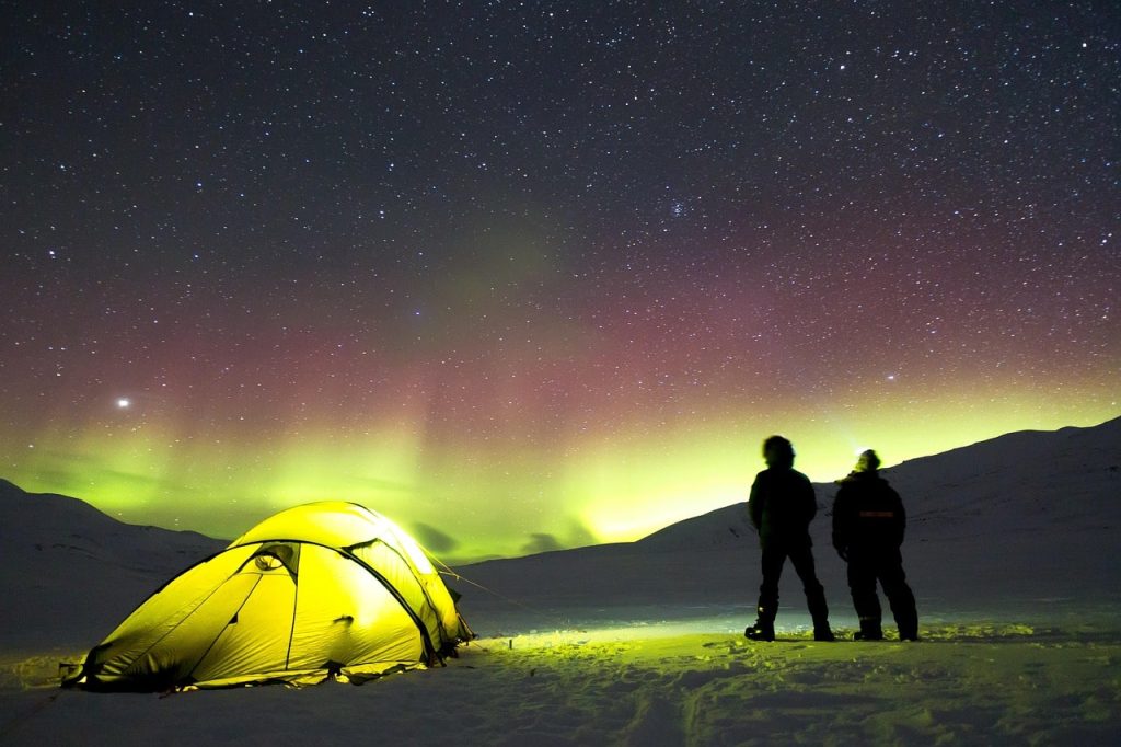 Aurores boréales à Tromsø en hiver avec tente et voyageurs observant le ciel arctique