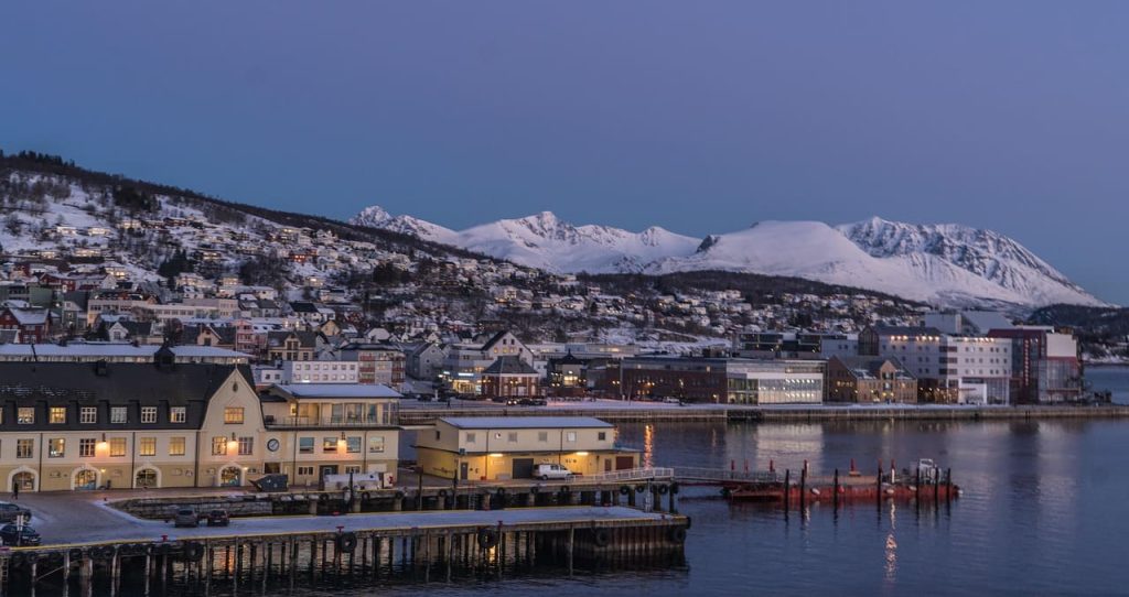 Vue de Tromso en hiver avec le port, les maisons colorées et les montagnes enneigées en arrière-plan
